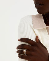 A model wears a round trio style engagement ring with a white diamond surrounded by white diamond either side stacked with diamond and plain wedding bands