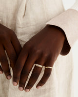 A model wears an array of diamond bands, from a round wrap ring to an alternate star set diamond band