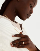 A model wears an emerald cut trio design engagement ring with our square profile wedding band and diamond cascade band