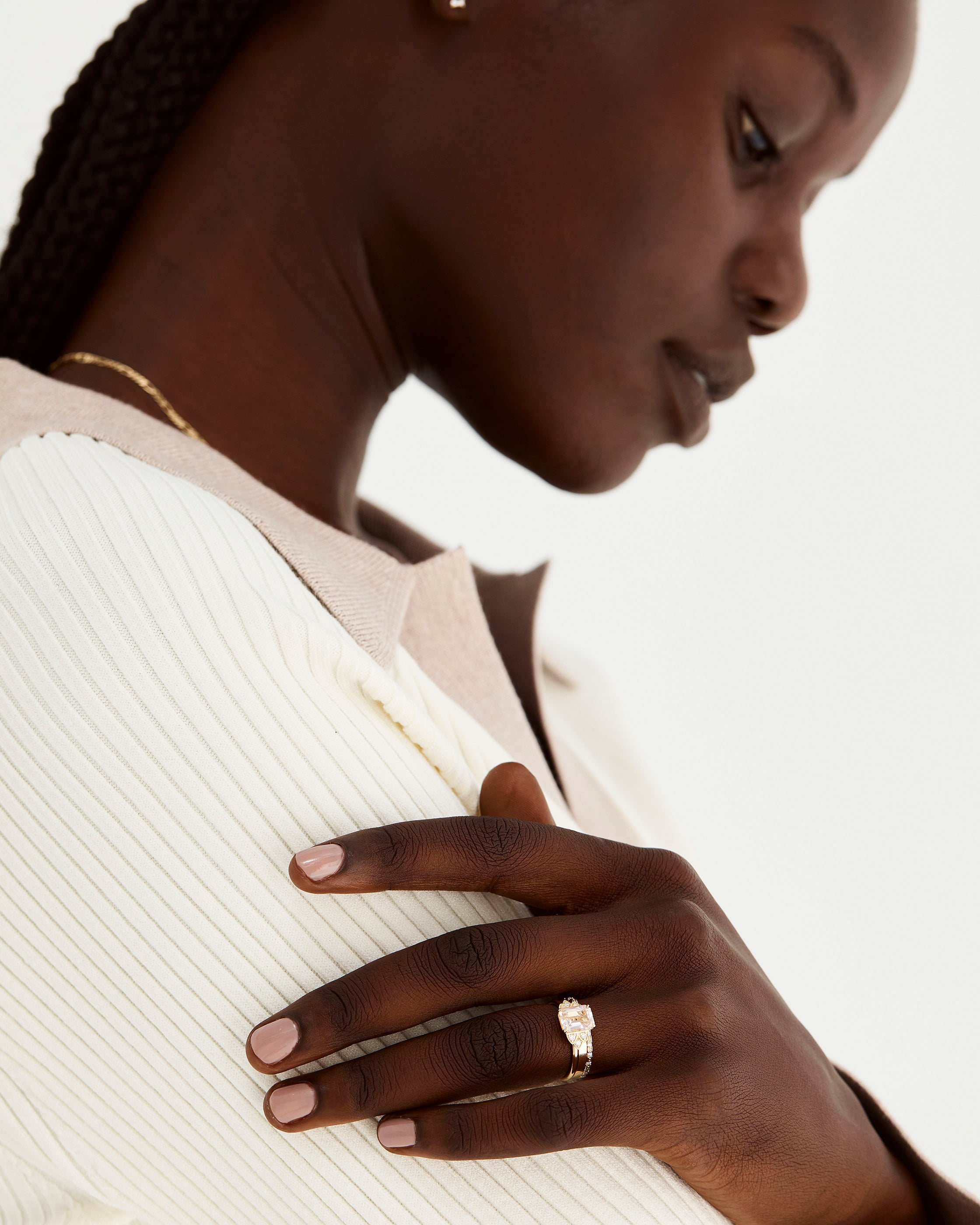 A model wears our oval morganite engagement ring, adorned with white diamonds either side and stacked with diamond and plain wedding bands