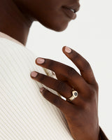 Model wears a sapphire halo engagement ring design with a gold band a cascade sapphire wedding ring