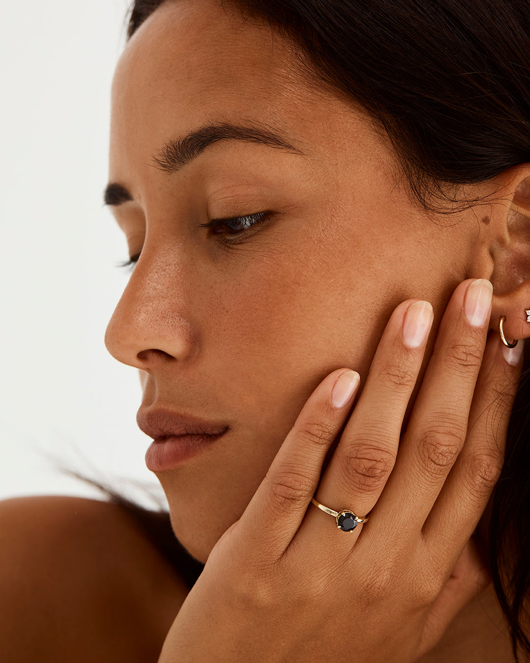 A model wearing a round solitaire style engagement ring with a black spinel.