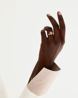 A model wears a hexagonal cut smokey quartz, surrounded by a halo of white diamonds stacked with a plain wedding band