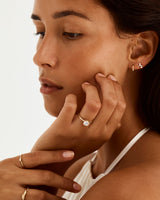 A model wears a round solitaire style engagement ring with a white diamond. 