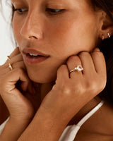 A model wears a round trio style engagement ring with a rutilated quartz surrounded by white diamond either side