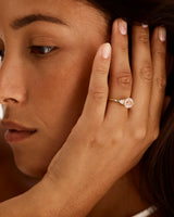 A model wears a round trio style engagement ring with a morganite surrounded by white diamond either side