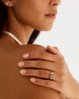 A model wears a round trio style engagement ring with a tourmalinated quartz surrounded by white diamond either side