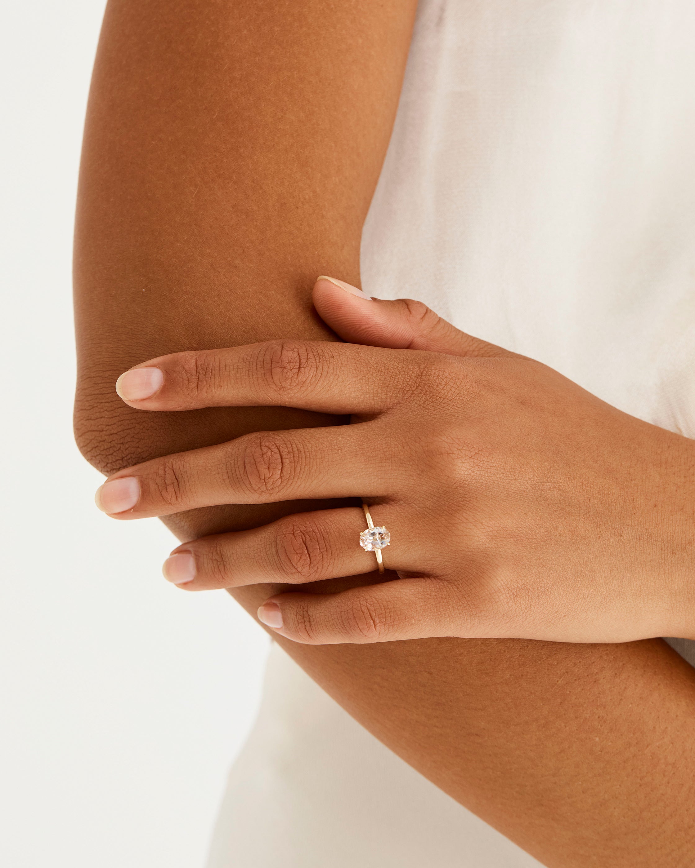 A model wears an oval solitaire style engagement ring with a rutilated quartz