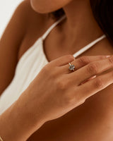 A model wears an oval solitaire style engagement ring with a tourmalinated quartz.