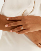 A model wears an oval trio style engagement ring with a rutilated quartz