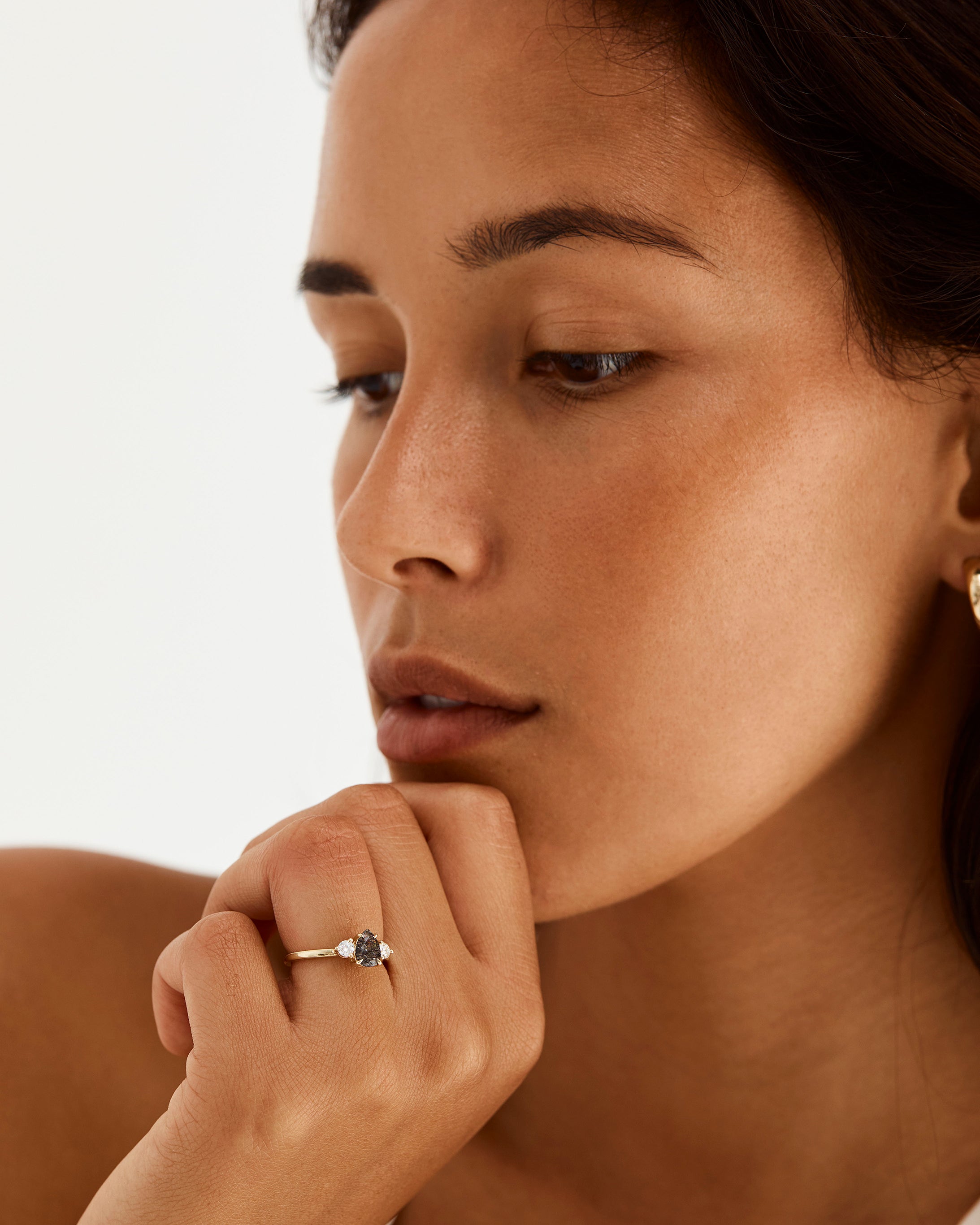 A model wears a pear cut trio engagement ring with diamond and tourmalinated quartz