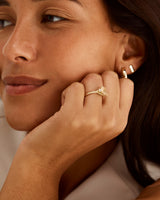 A model wears an emerald cut trio ring featuring petite diamonds and a central savannah sunstone