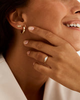 An engagement ring with woven shoulders inlayed with white diamonds is worn by a model