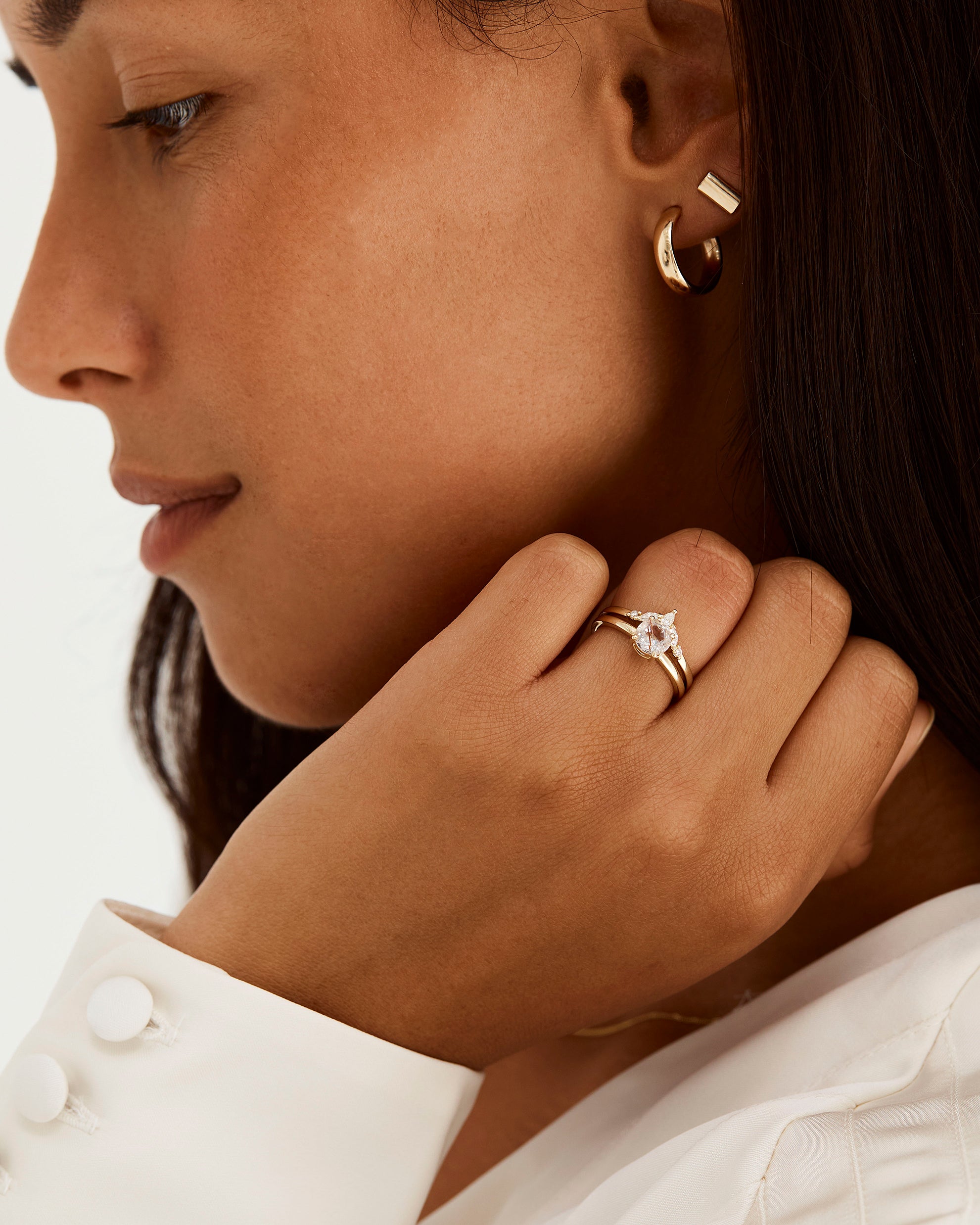 A model wears a diamond crown ring stacked with a solitaire style engagement ring