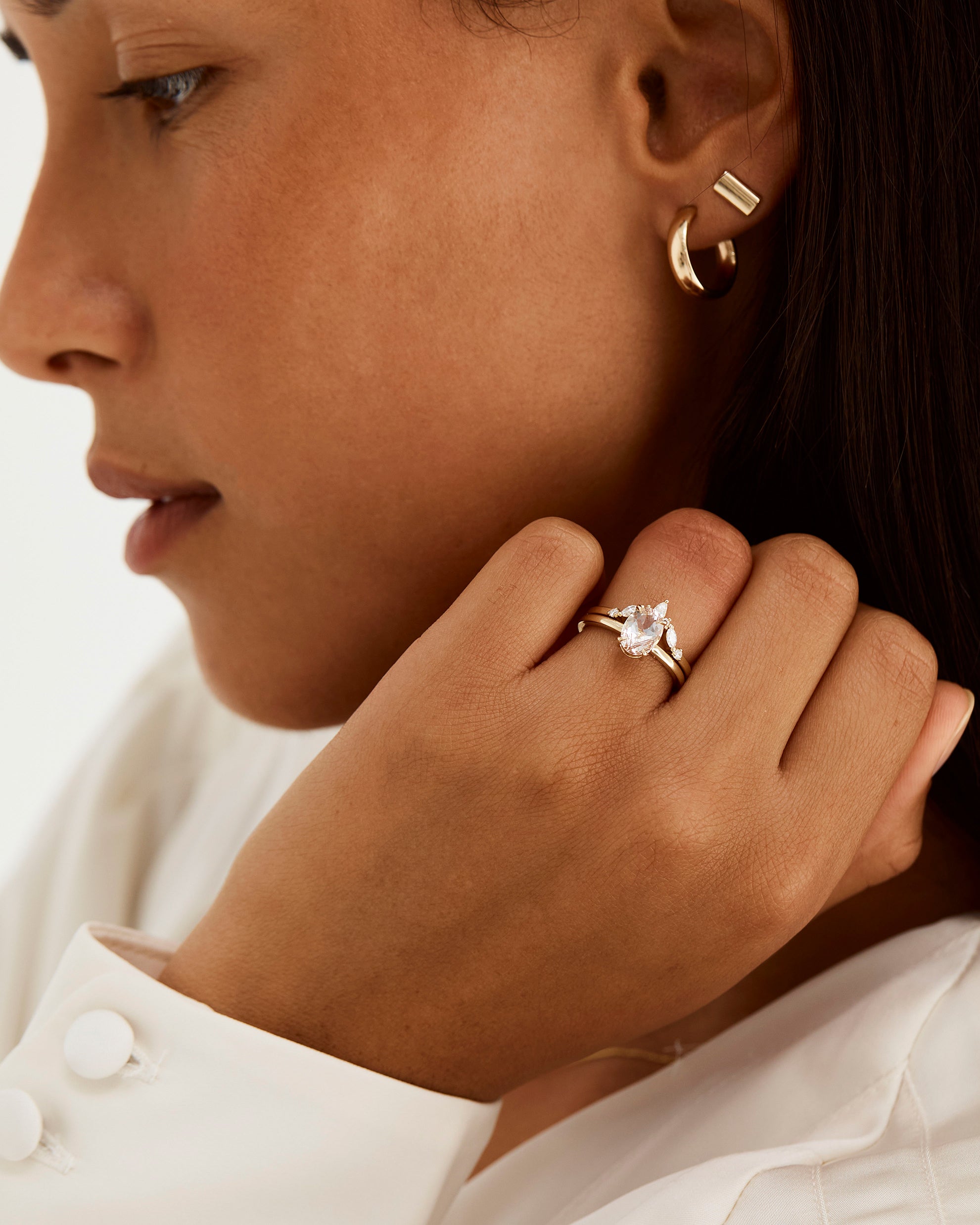 A model wears a diamond crown ring stacked with a solitaire style engagement ring