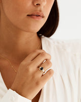A model wears a gentle arc crown ring stacked with a trio style engagement ring