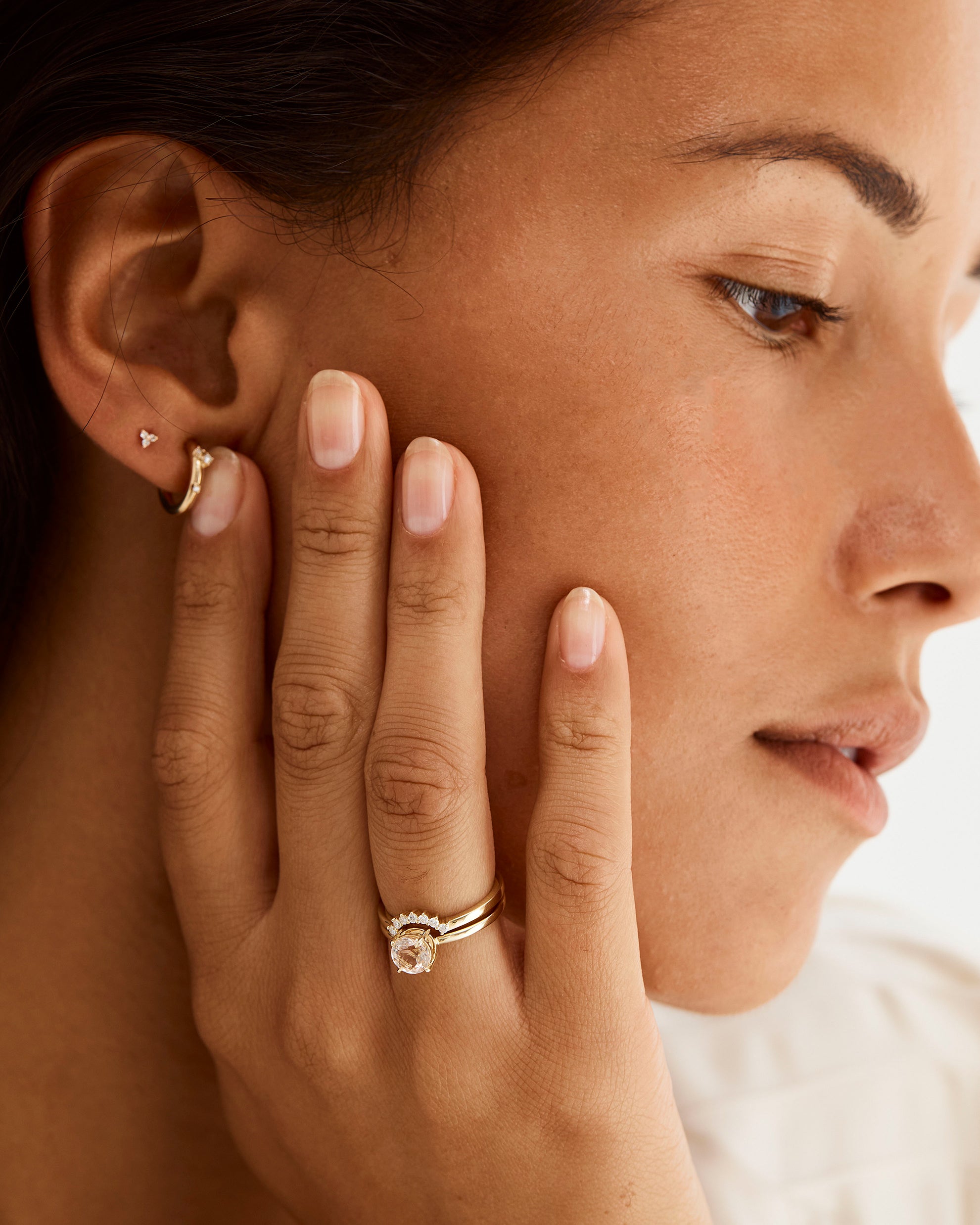 A model wears a diamond crown ring stacked with a solitaire style engagement ring