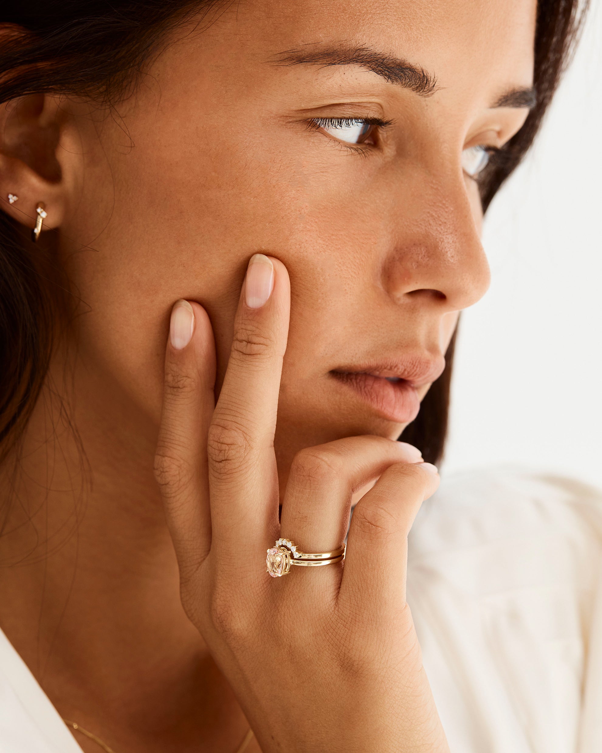 A model wears a diamond crown ring stacked with a solitaire style engagement ring