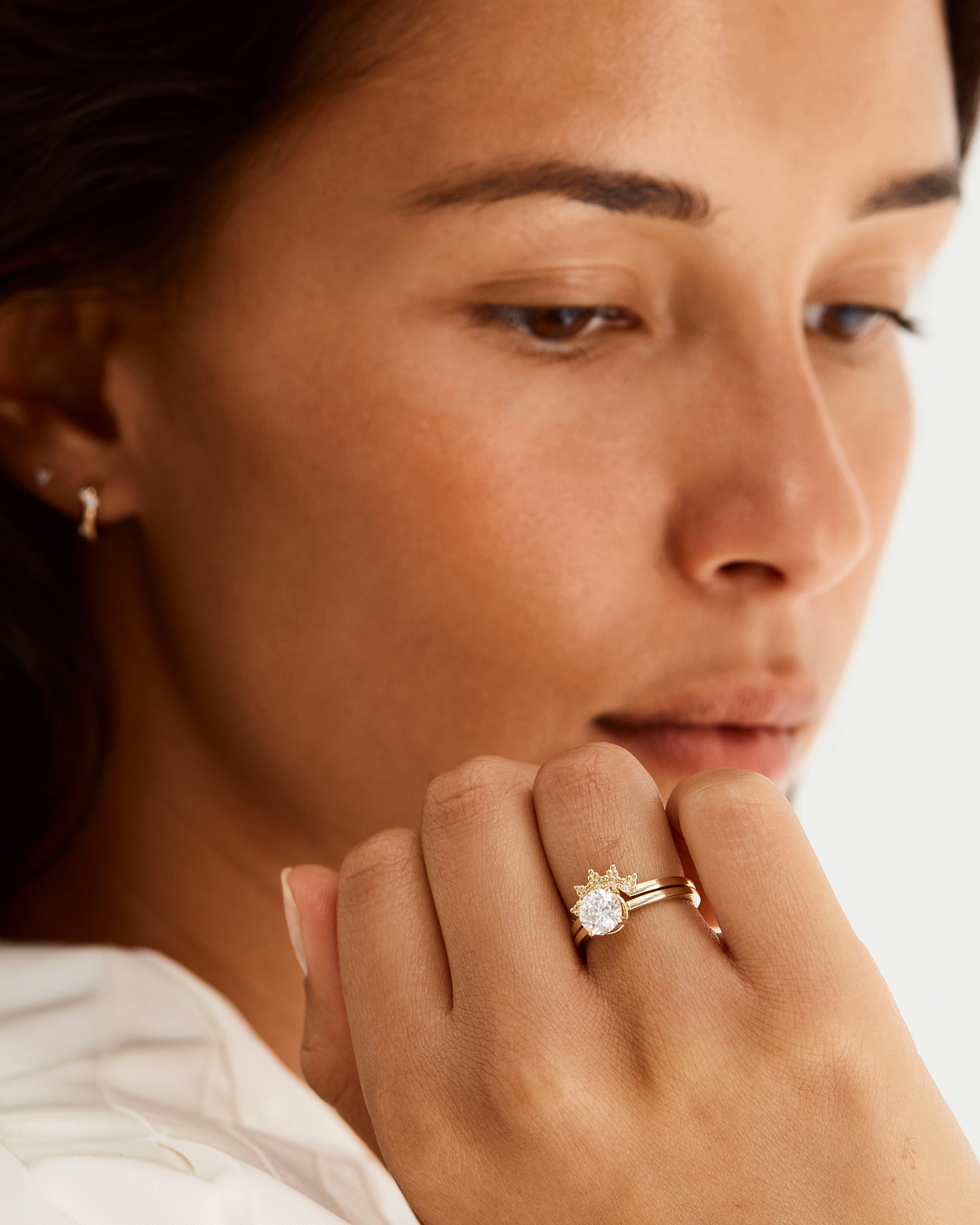 A model wears a diamond dot detailed crown ring stacked with a solitaire style engagement ring