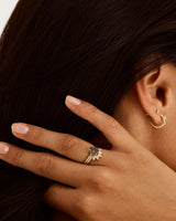 A model wears a diamond dot detailed crown ring stacked with a solitaire style engagement ring