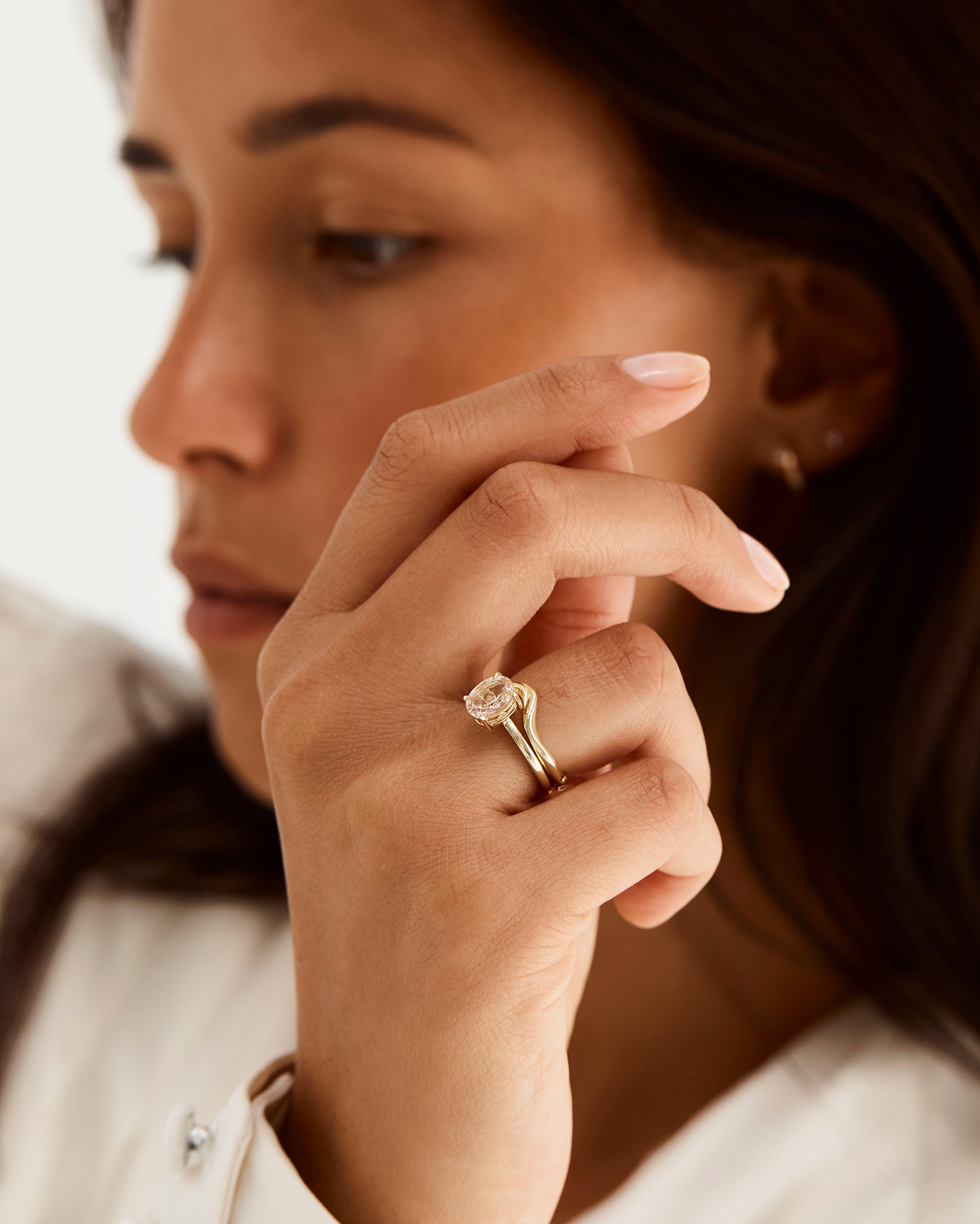 A model wears an organic inspired crown ring stacked with a solitaire style engagement ring