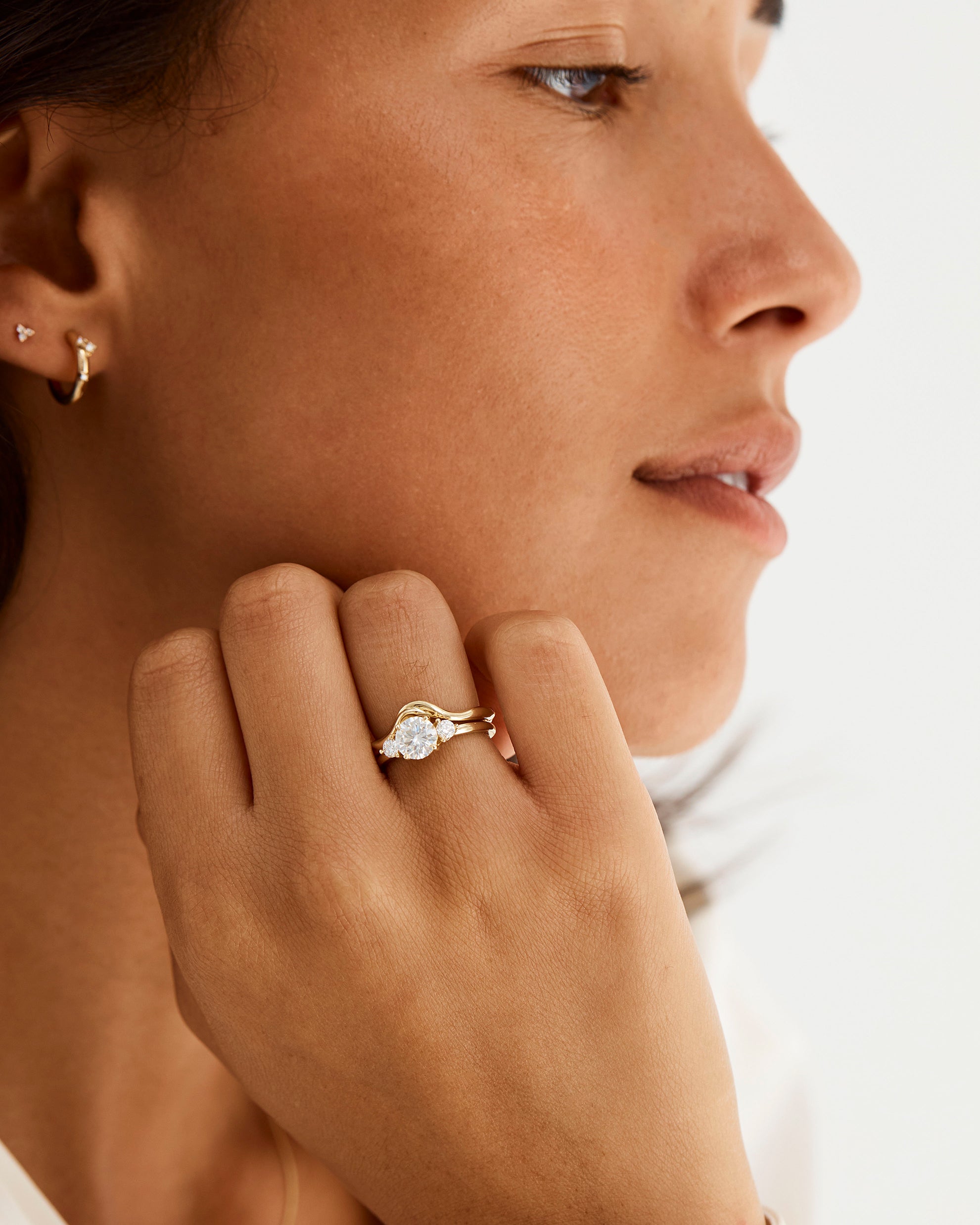 A model wears an organic inspired crown ring stacked with a trio style engagement ring
