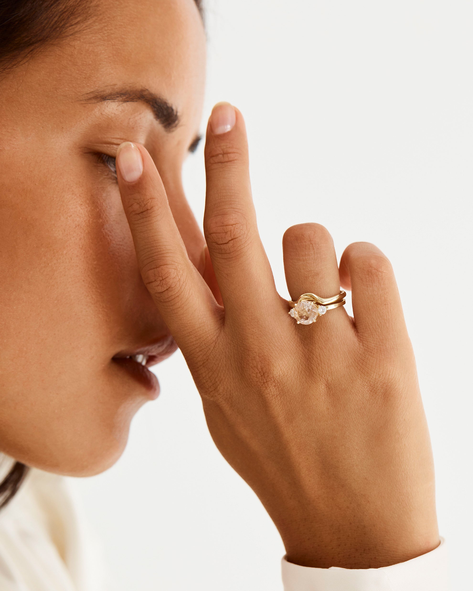 A model wears an organic inspired crown ring stacked with a trio style engagement ring