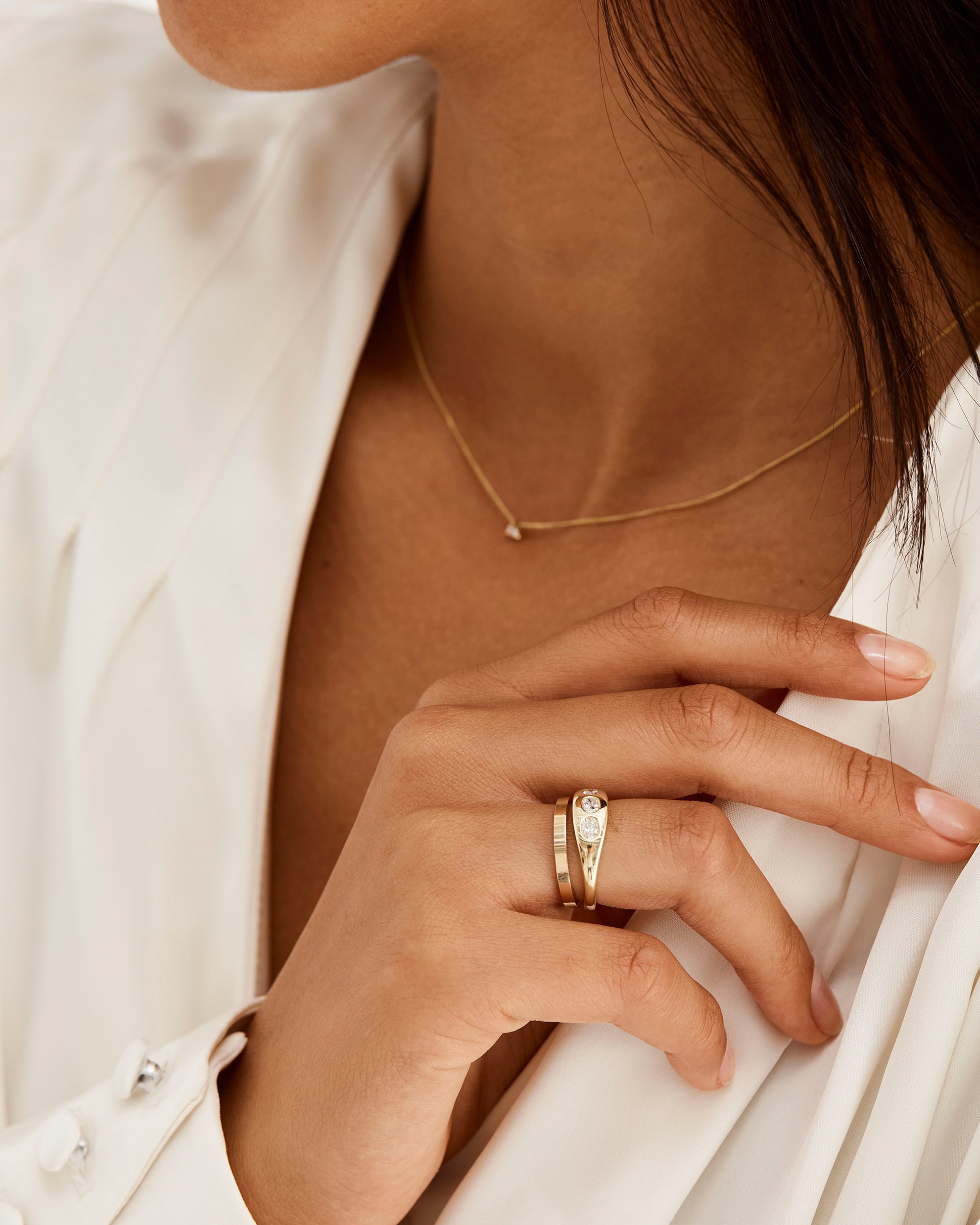 A signet shaped ring with three oval cut diamonds, worn on model with a fine square profile band