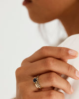 A model wears a solitaire style engagement ring, featuring a round cut Australian sapphire, with diamonds in and around the setting