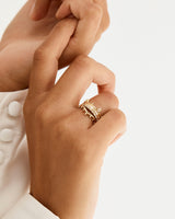 Model wearing a stack of wedding bands with unique detailing, including a dotted gentle point ring, dine diamond cascade band, 2mm gold band with millgrain detail and a diamond cluster inspired band.  