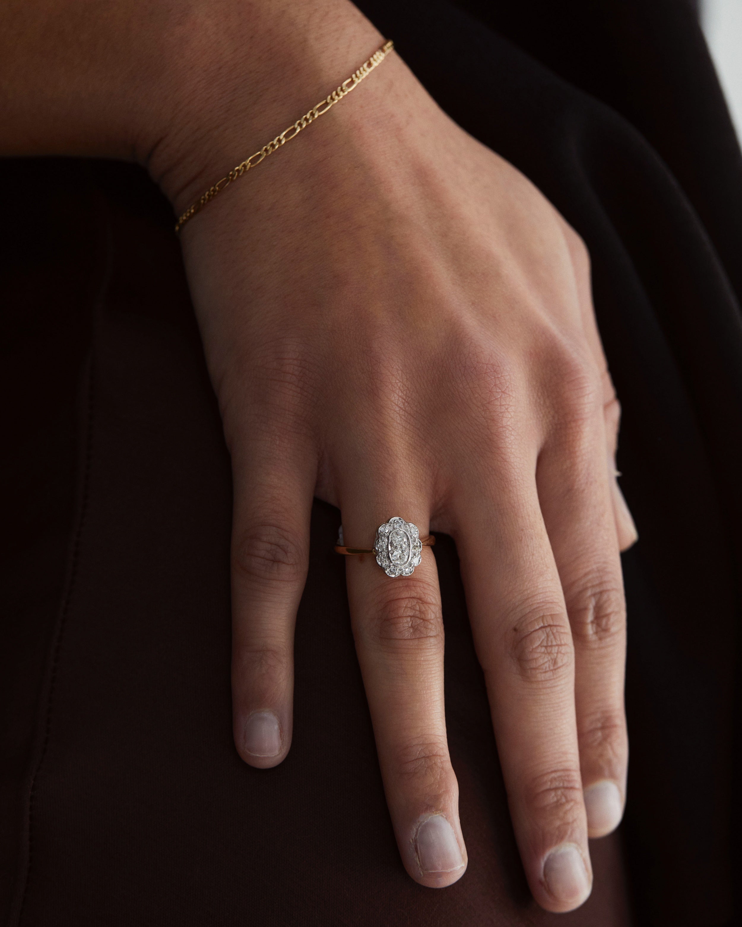 A hand adorned with the Clementine Vintage Ring | Diamonds and the Figaro Chain Bracelet