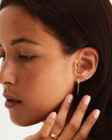 Woman wearing gold earring with a white diamond and a chain