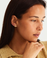 A model wears the pan studs stacked with tiny dot studs in yellow gold