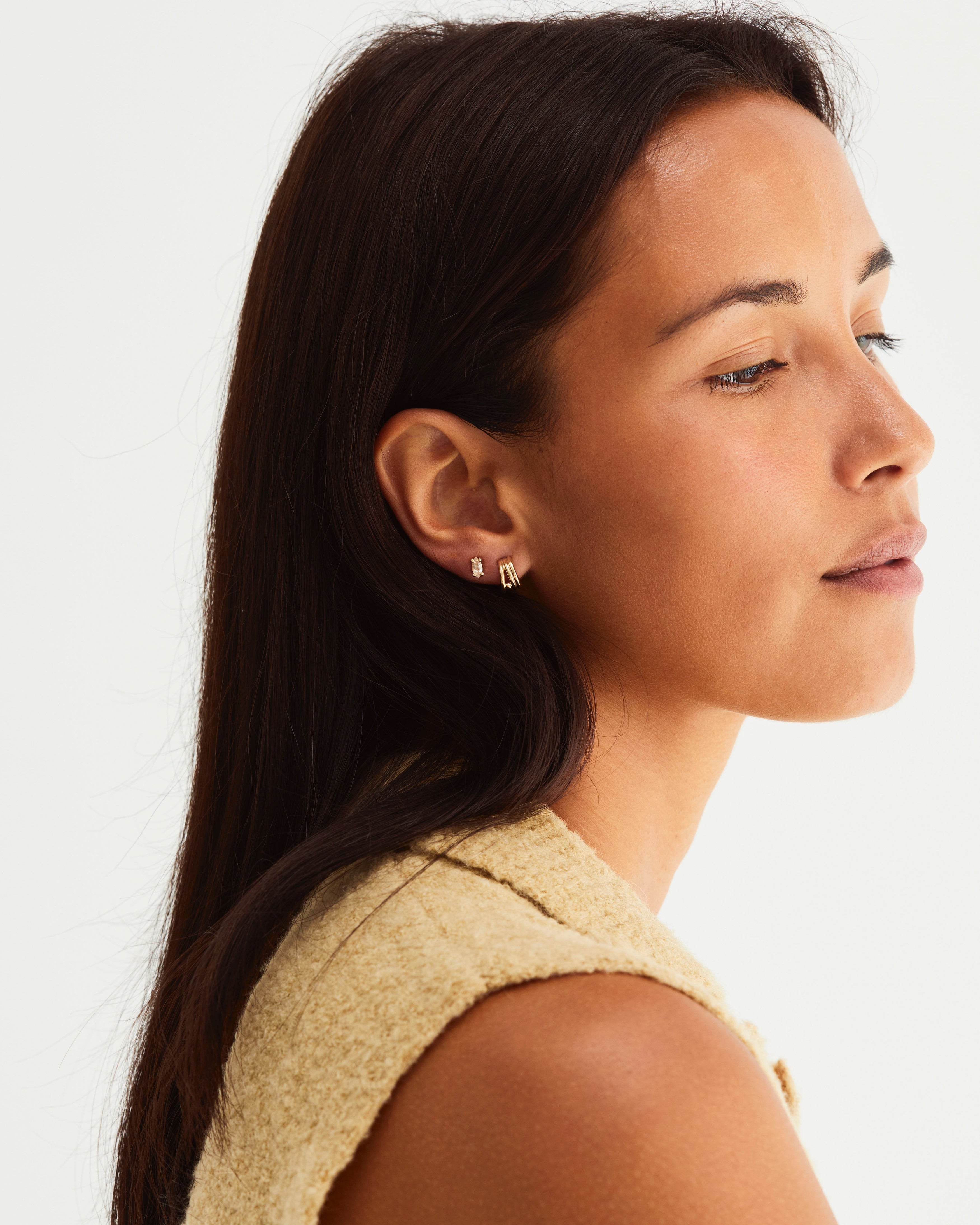 Woman wearing gold hoops and marquise shaped studs with a honey coloured stone