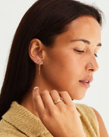 Woman wearing a diamond round stud and a diamond cluster chain earring