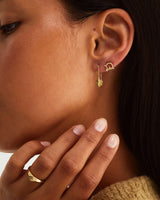 Woman wearing drop earrings with a white diamond in yellow gold