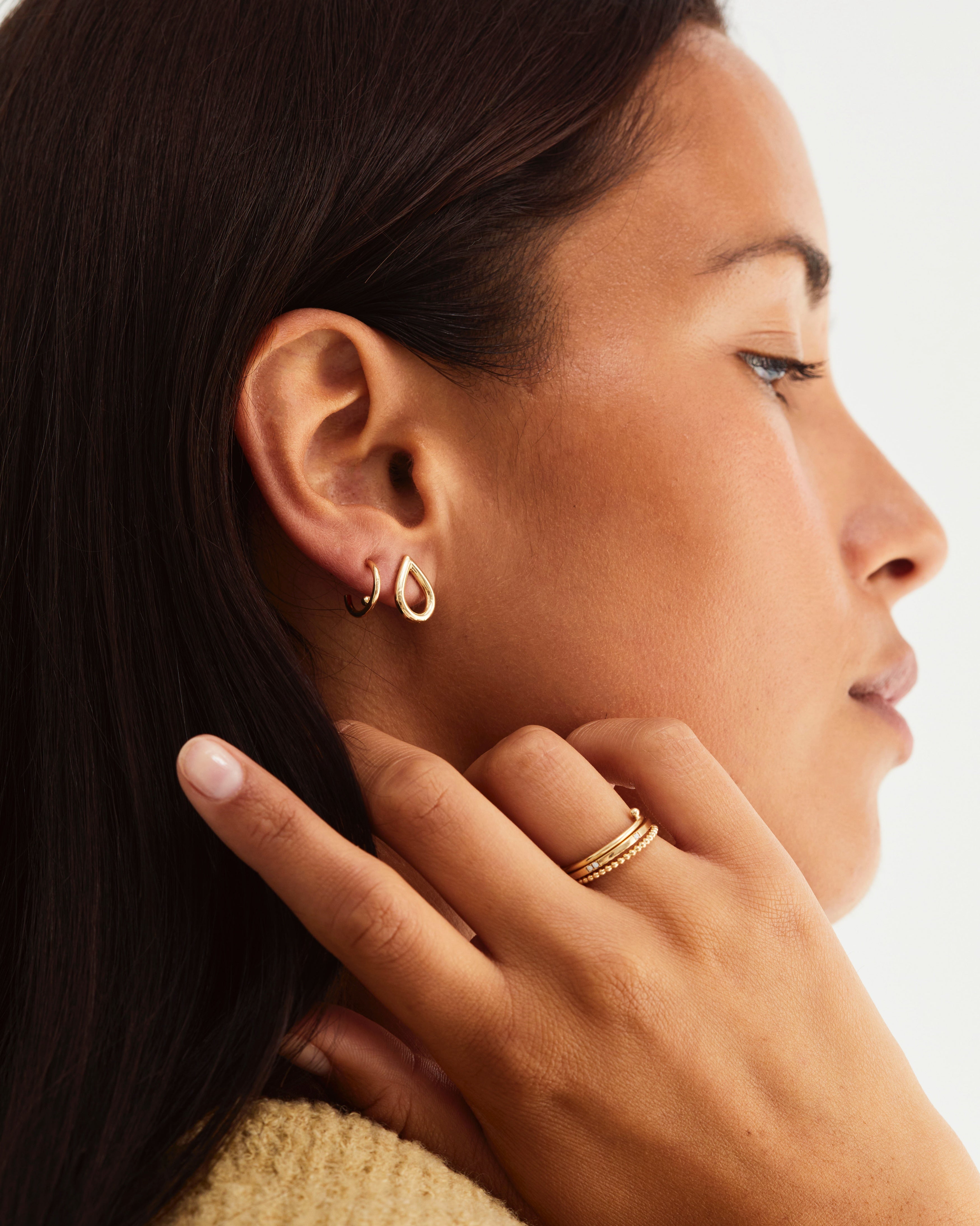 A woman wearing a ring stack featuring the Dotted Stacking Ring, Antares Ring | Birthstone and the Balance Ring, all in yellow gold.