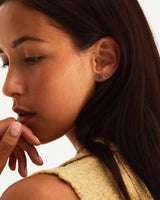 A woman wearing the Una Studs | Tourmalinated Quartz and the Cara Studs, both in yellow gold.
