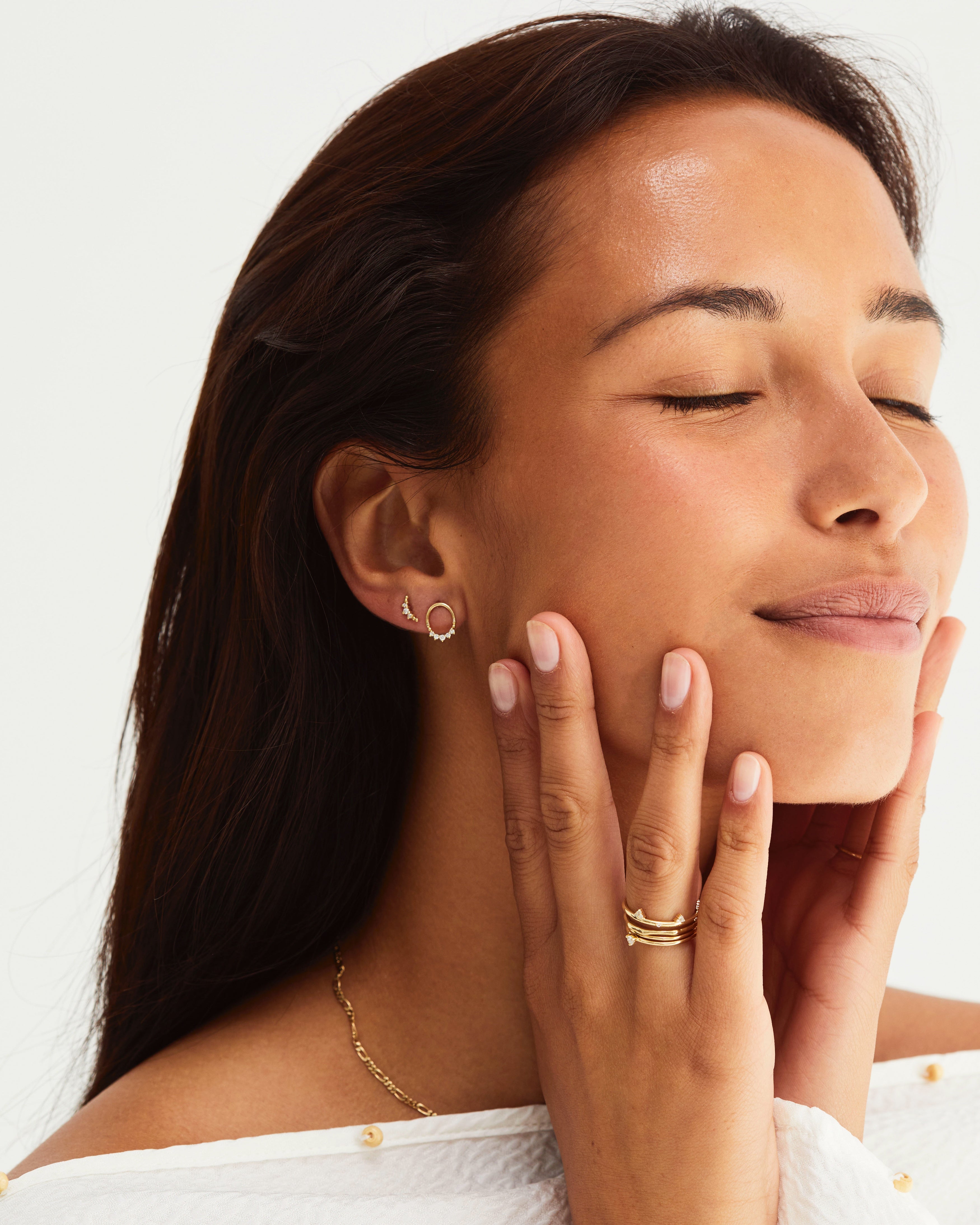 A woman adorned in yellow gold jewellery, including the Mahina Studs | Diamonds and the Crescent Studs | Diamonds. 