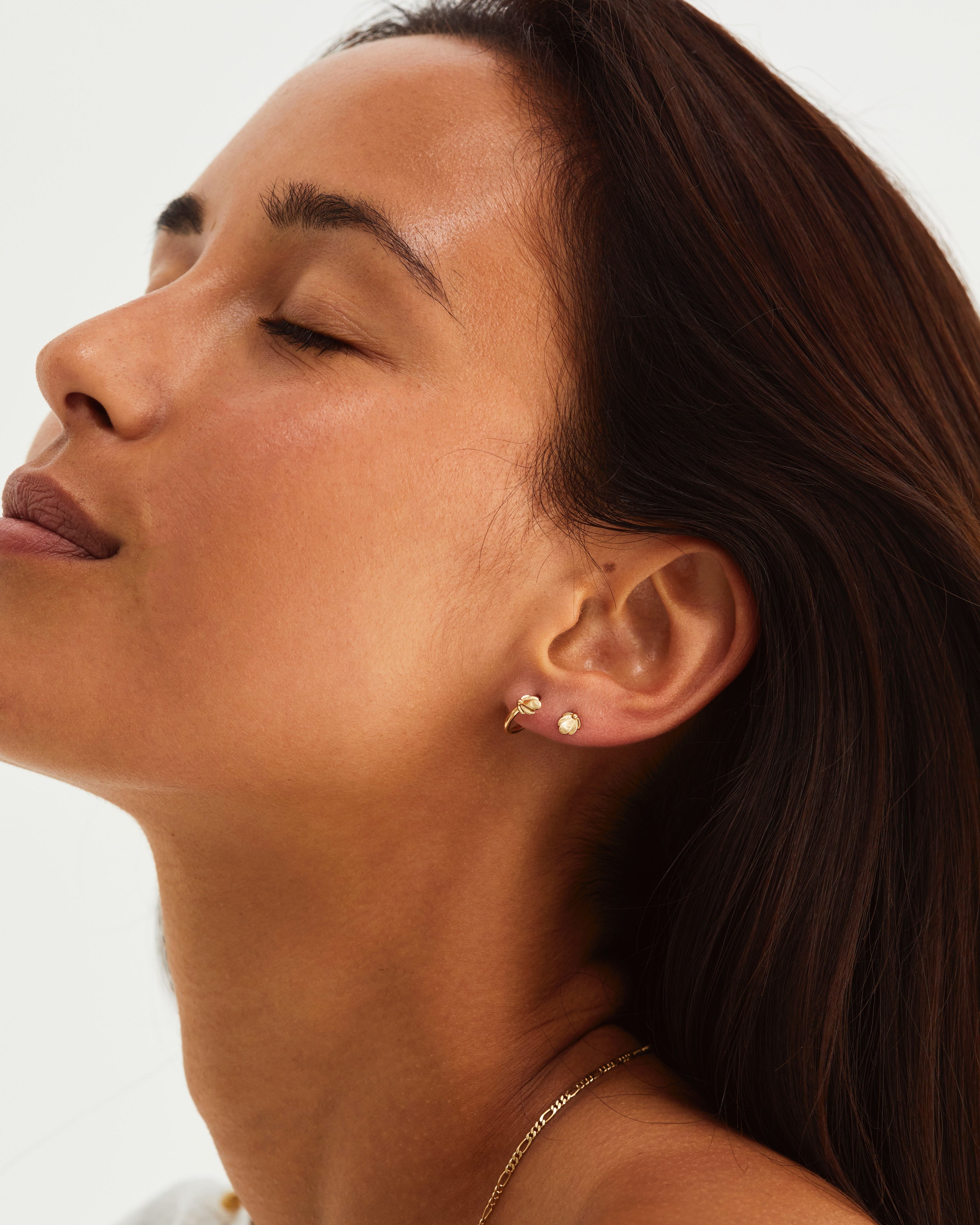 A woman wearing the Aeris Hoops and Aeris Studs in yellow gold.
