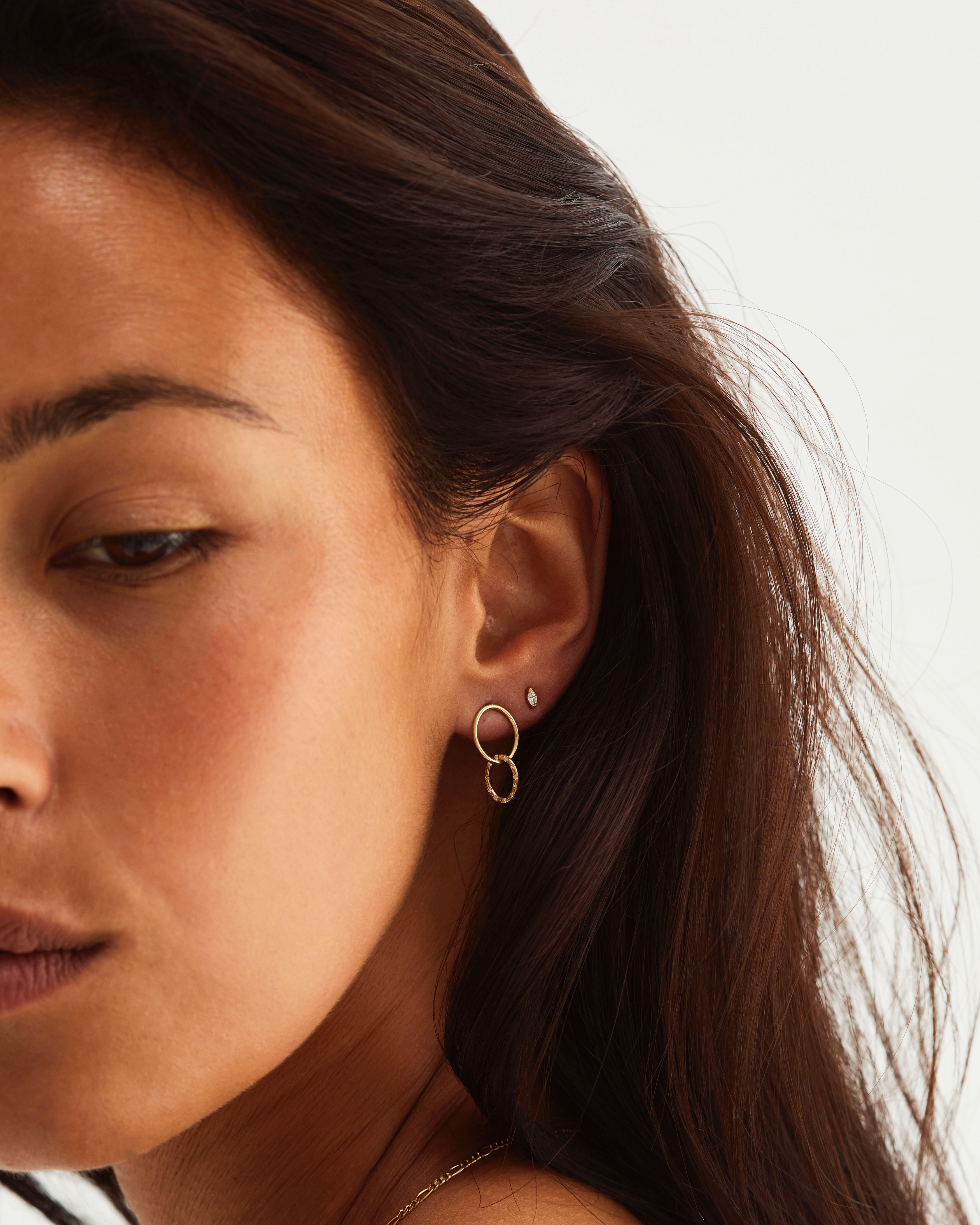 A woman wearing the Cascade Loop Through Oval Studs | Diamonds in yellow gold.