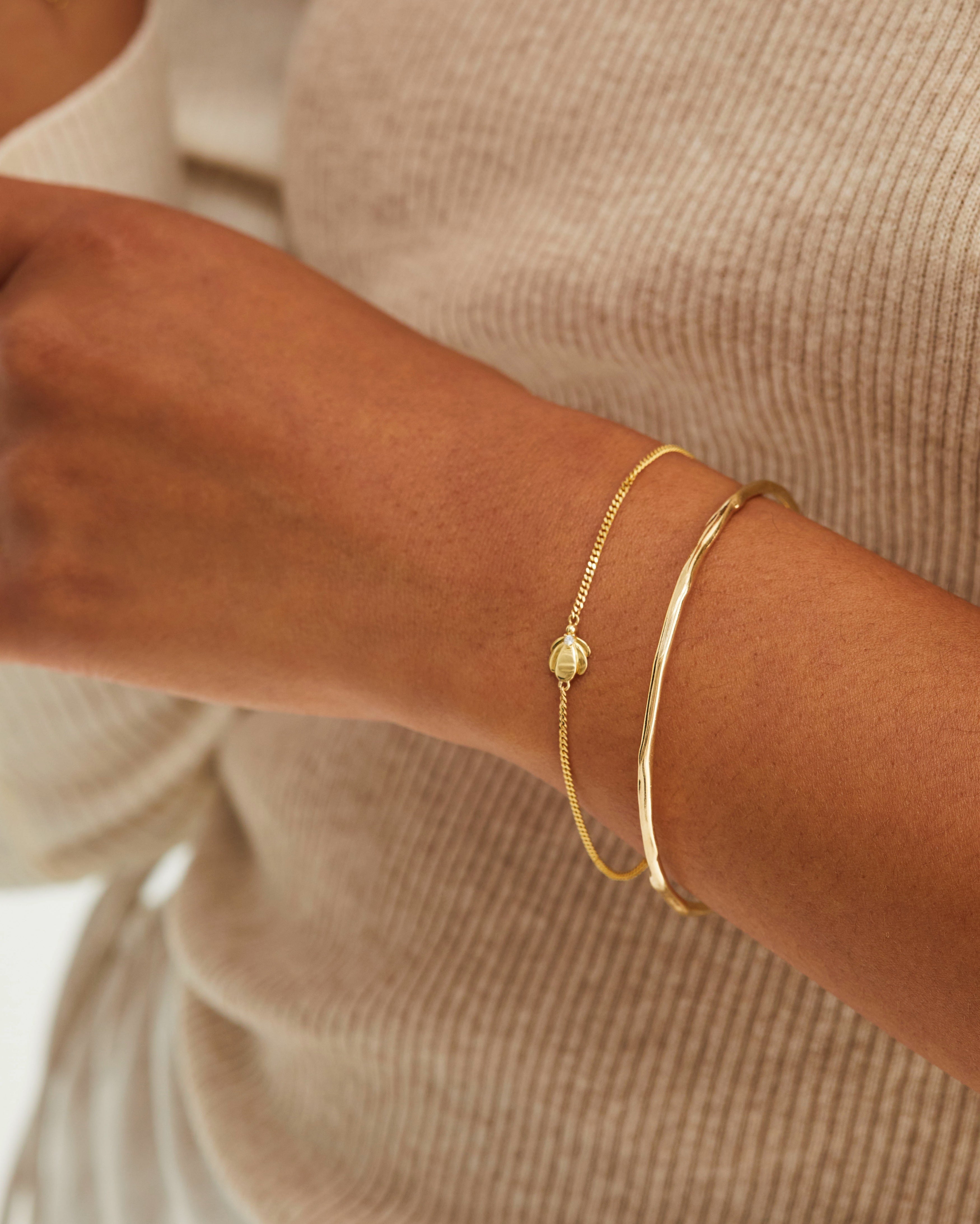 A woman wearing the Aeris Bracelet | Diamond and the Organic Bangle, both in yellow gold.