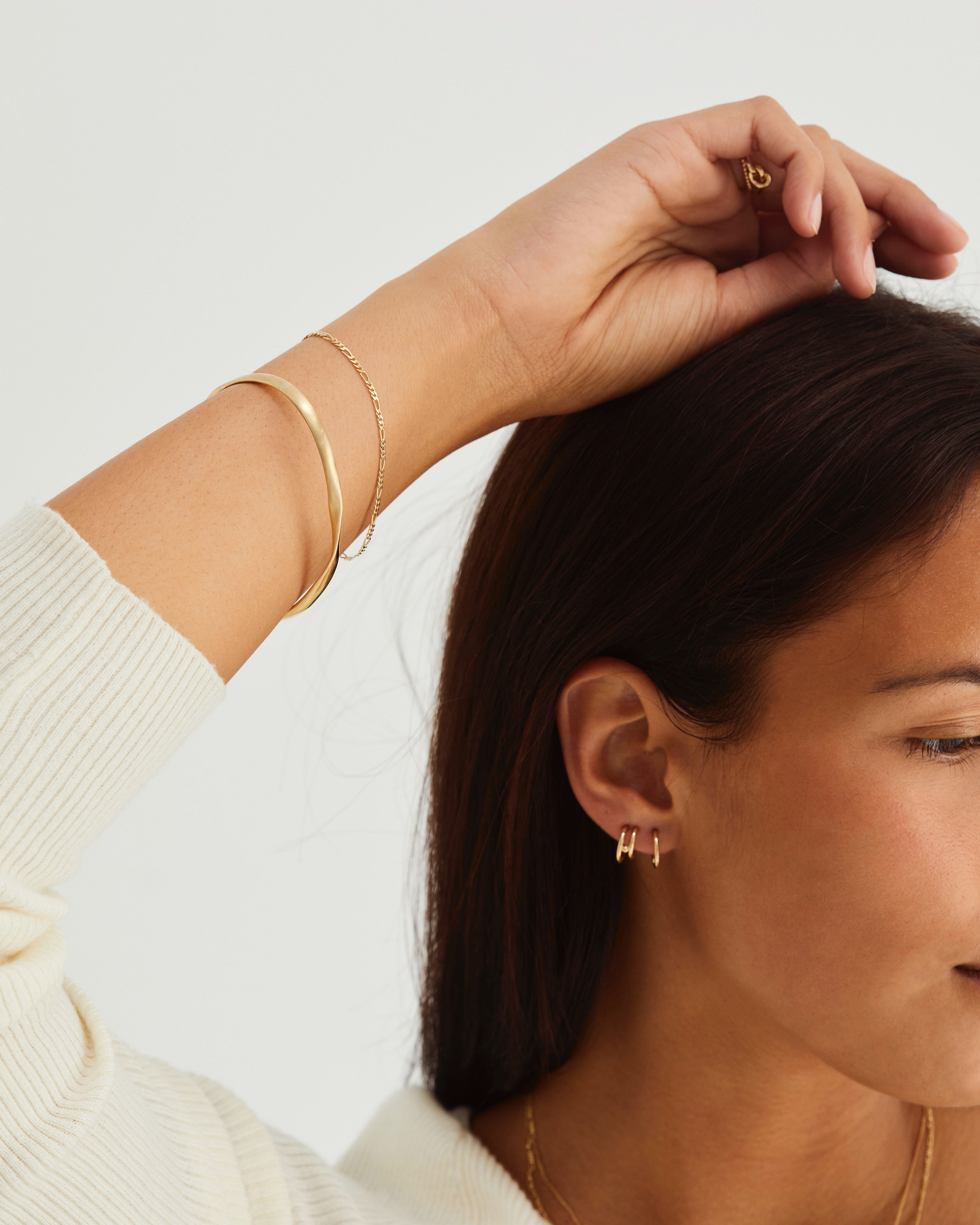 A woman wearing the Ellipse / Shift Bangle in yellow gold.