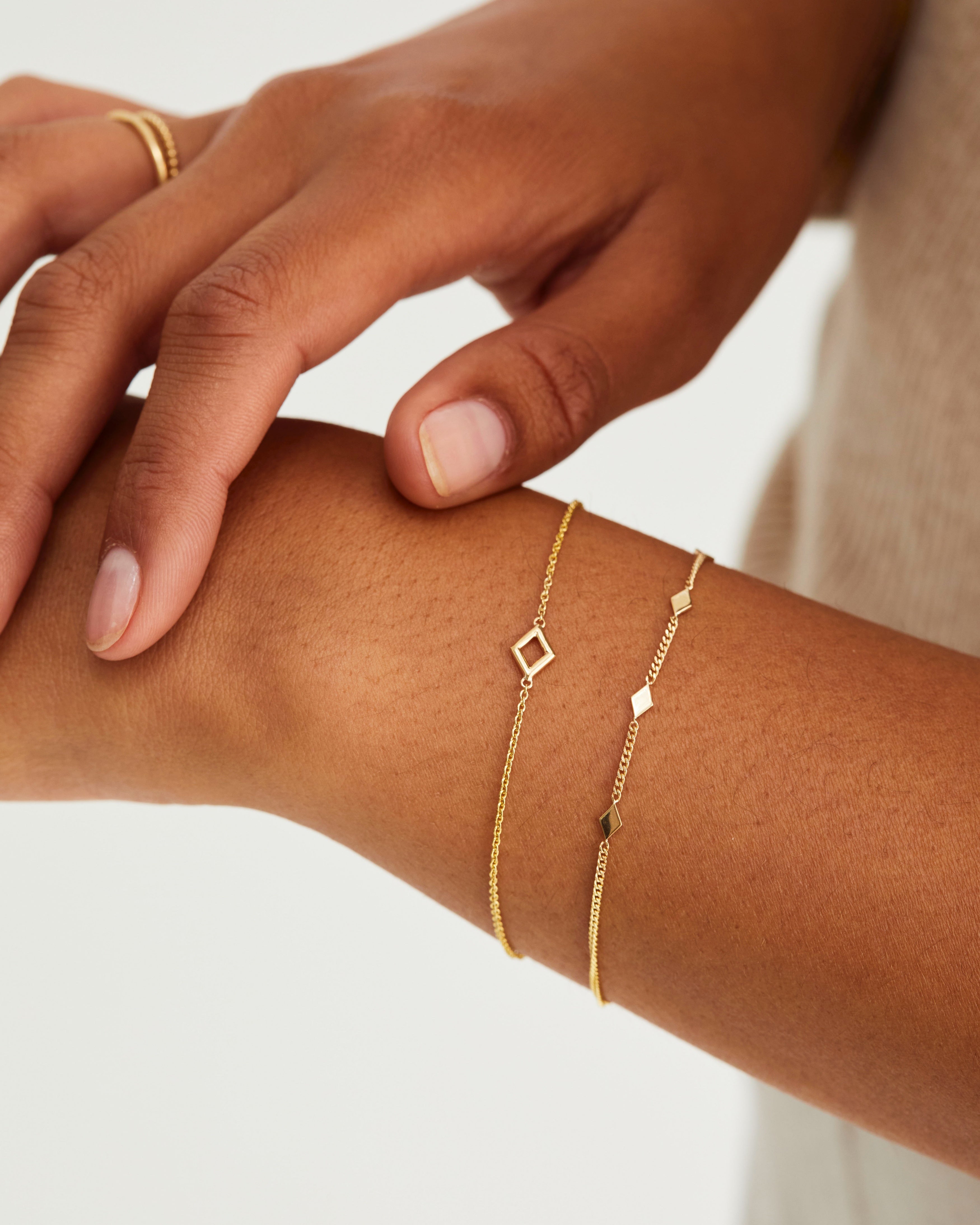 A woman wearing the Nuna Bracelet and the Nuna Charm Bracelet, both in yellow gold.