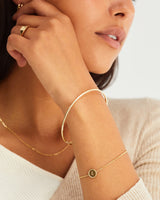 A woman wearing the Precious Initial Bracelet | Birthstone in yellow gold.