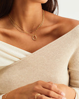Model wears a gold pendant layered with fine chain