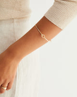 A woman wearing the Oana Bangle in yellow gold.