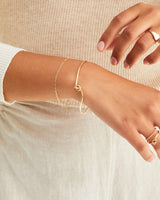 Model wears our Figaro chain bracelet with a knot inspired bangle in yellow gold