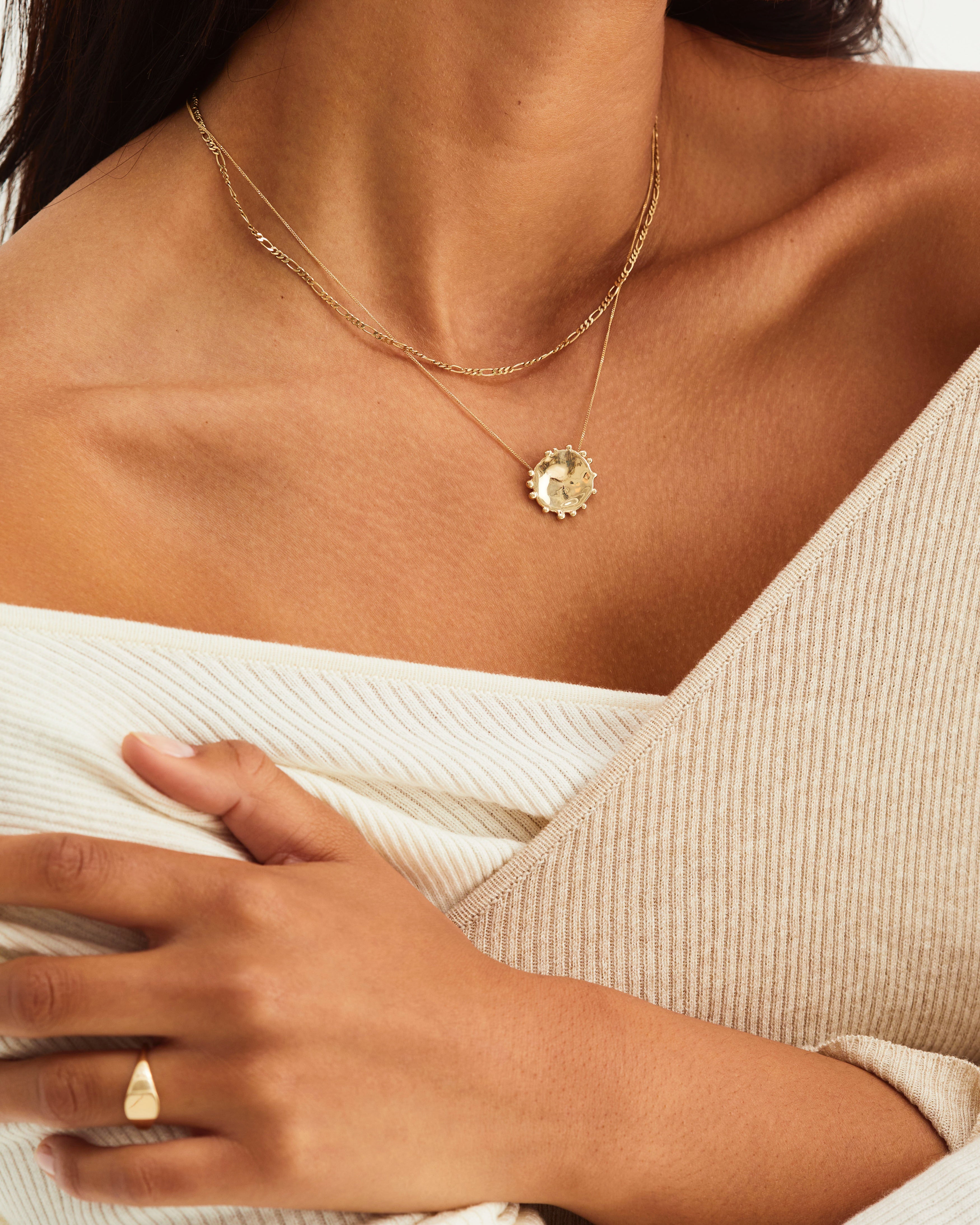 A woman wearing the Dotted Mana Necklace in yellow gold.
