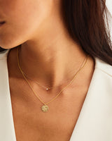 A woman layering the Spotted Orchid Necklace and the Danaë Slider Necklace | Diamond, both in yellow gold.